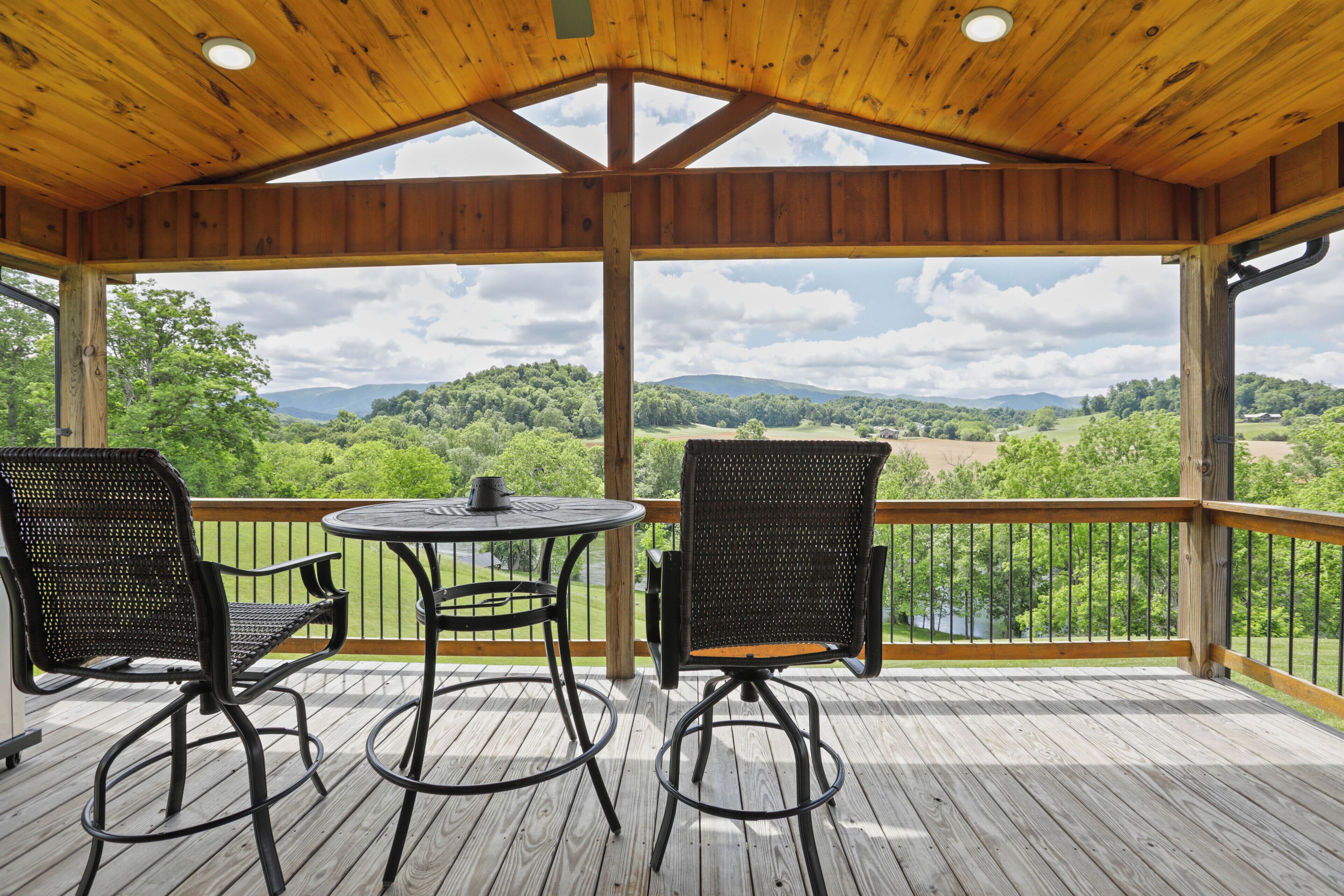 Une terrasse extérieure couverte, dotée de deux chaises et d’une table, qui offre une vue sur un paysage magnifique.