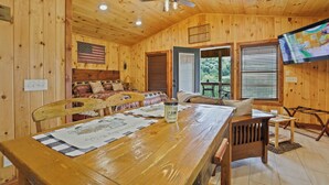 A wooden cabin interior with a dining table, chairs, a ceiling fan, and a television mounted on the wall. - Ruth's Retreat on South Holston River  (Bristol)