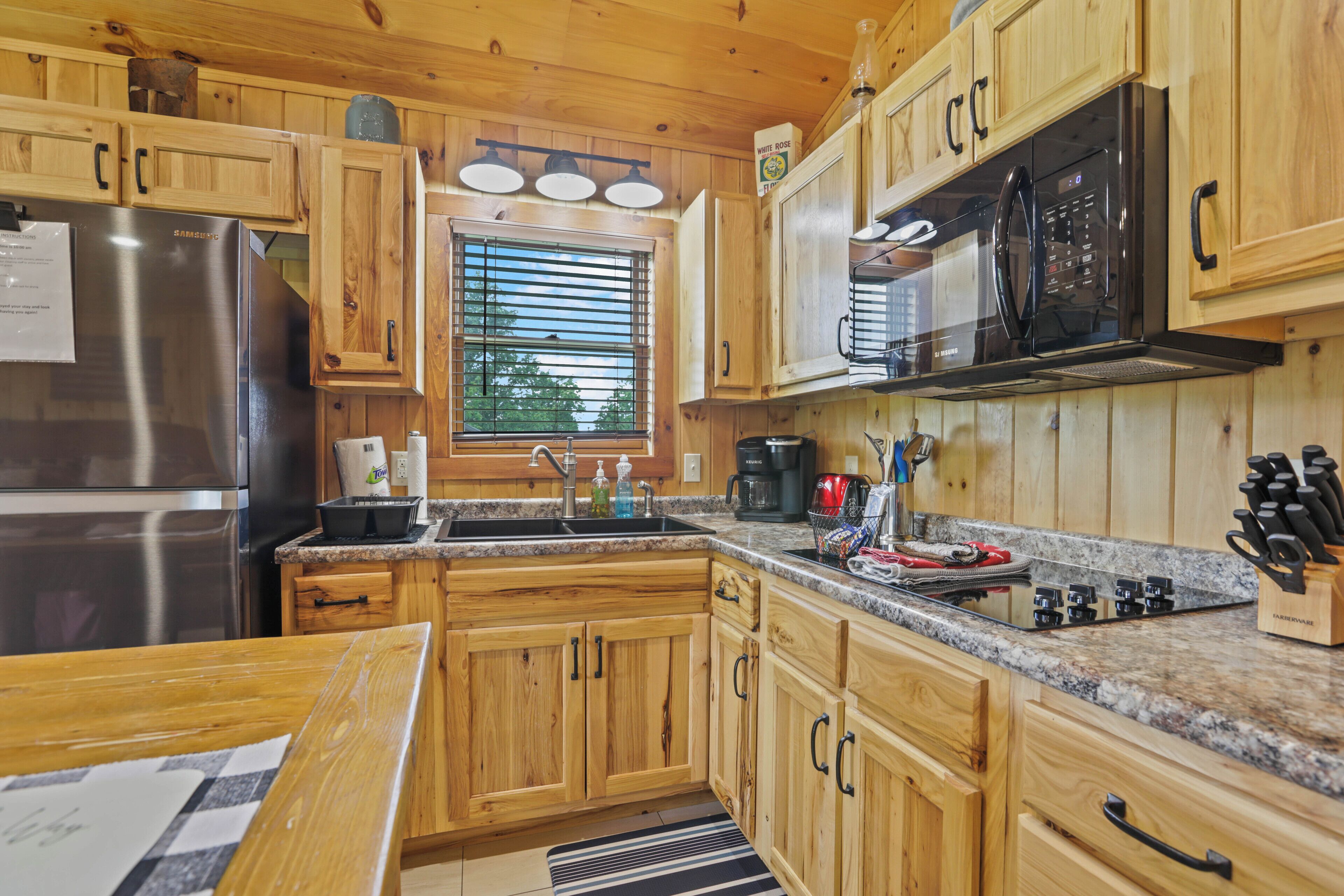 A kitchen with wooden cabinets, a stainless steel refrigerator, a microwave, and a granite countertop.