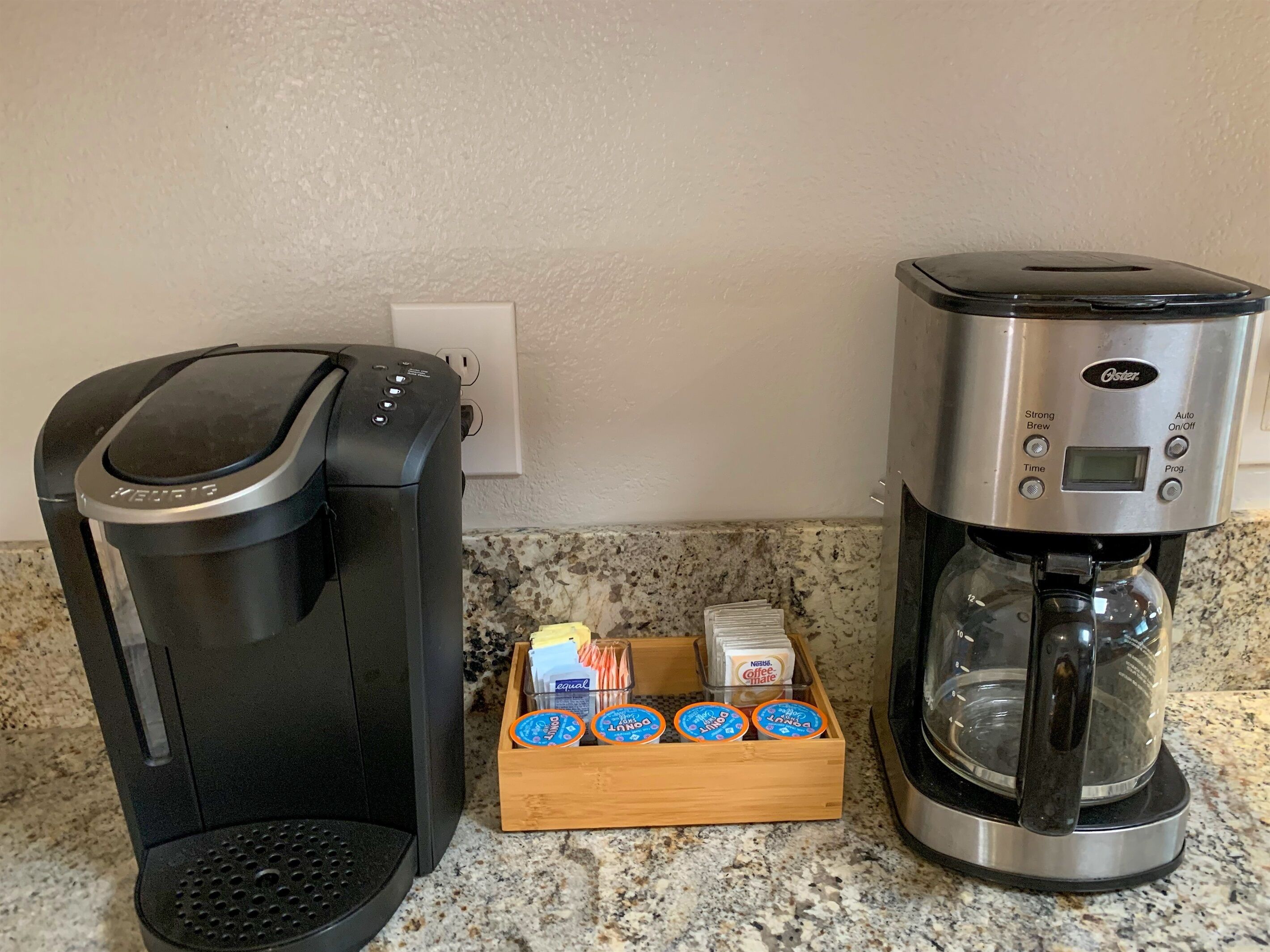 A coffee maker and a coffee pot on a kitchen counter with a coffee pod holder.