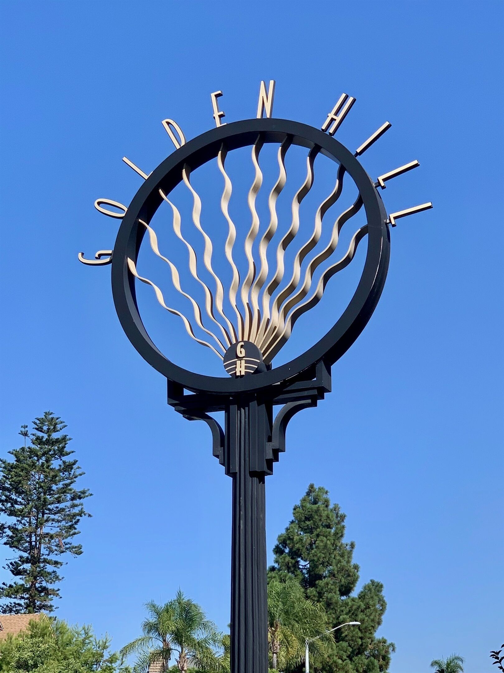 Un panneau circulaire portant les mots « Golden Hill » et un motif stylisé représentant un soleil.