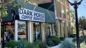 Ein Gebäude mit einem Schild für 'Dark Horse Coffee Roasters' und 'Mutual Friend'.