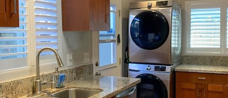 Una cocina moderna con encimeras de granito, electrodomésticos de acero inoxidable, armarios de madera y lavadora y secadora integradas.