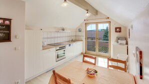 Une cuisine avec des meubles blancs, une table à manger avec des chaises et une fenêtre donnant sur un beau paysage.