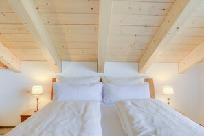 Une chambre avec deux lits, des poutres en bois au plafond et des lampes de chevet.