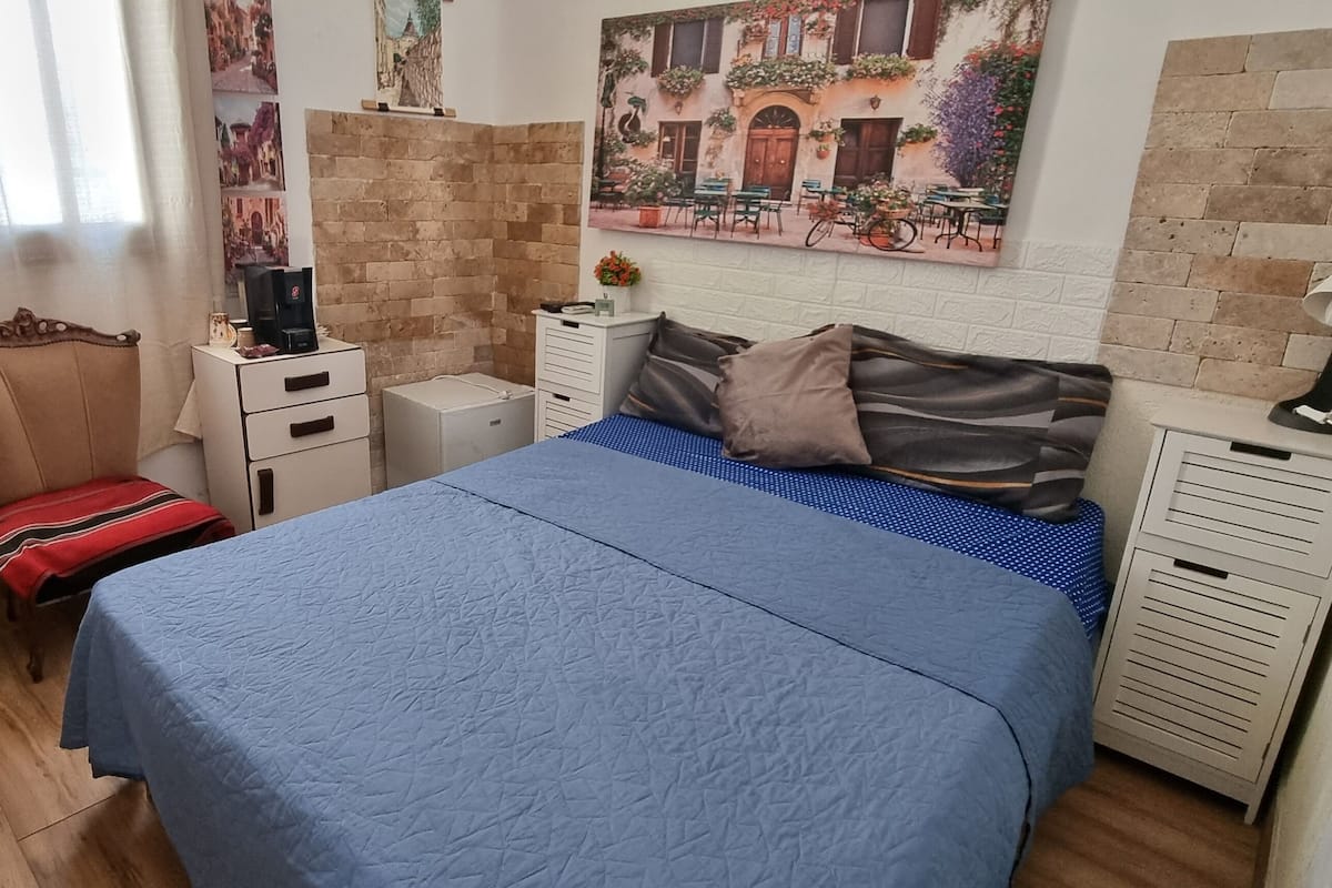 A bedroom with a bed, a nightstand, a dresser, a chair, and a door.