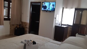 Une chambre d’hôtel avec un lit, un téléviseur fixé au mur, un lavabo et un miroir.