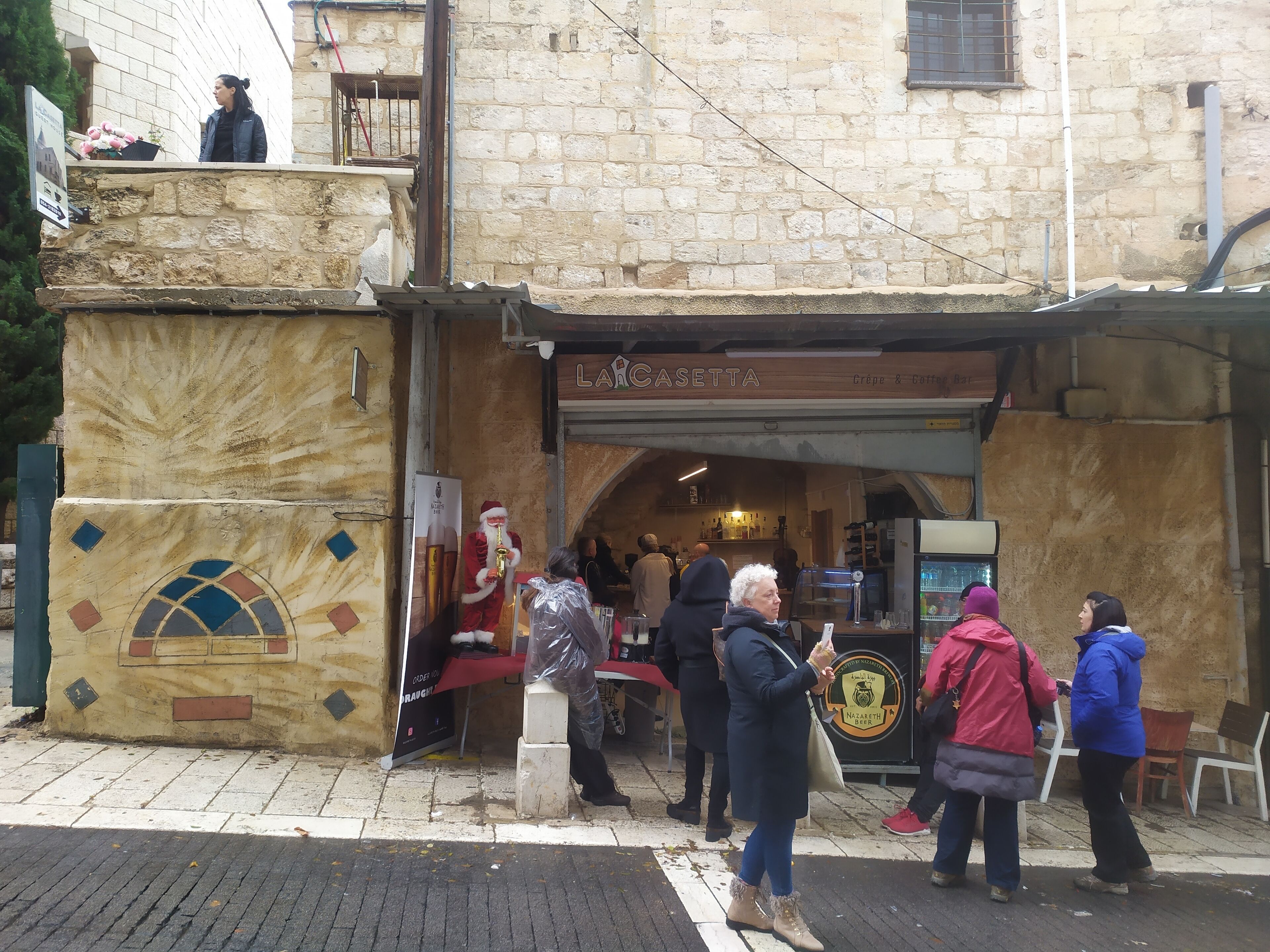 A stone building with a café named "LARCASETTA" and a Santa Claus figure outside.