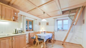 Una cocina con armarios de madera, una mesa de comedor con sillas, una ventana con cortinas y un techo de madera.