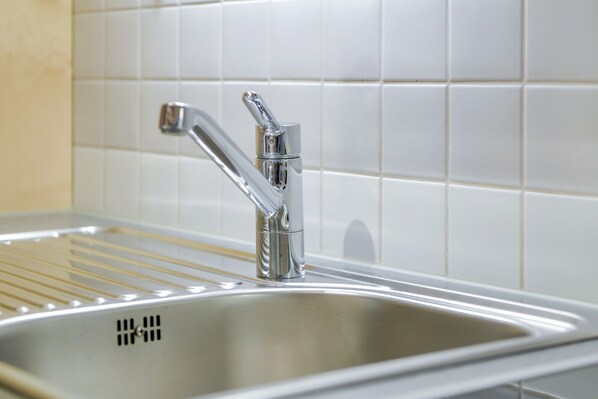 A stainless steel kitchen sink with a modern faucet, a drying rack, and a tiled backsplash. - Holiday Apartment "Sommerwind" with Mountain View, Garden & Balcony (Wackersberg)