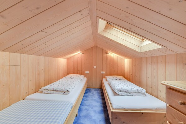 A wooden cabin with two single beds, a small dresser, and a skylight. - Holiday Apartment "Sommerwind" with Mountain View, Garden & Balcony (Wackersberg)