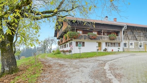 A traditional building with a balcony, a signboard, and a paved path. - Holiday Apartment "Sommerwind" with Mountain View, Garden & Balcony (Wackersberg)