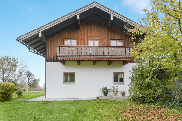 Ein zweistöckiges Holzhaus mit Balkon, weißer Fassade und einem Rasen.