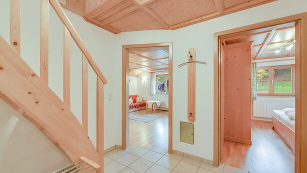 A spacious hallway with wooden flooring, a staircase, and a view into a room with a bed and a window. - Holiday Apartment "Sommerwind" with Mountain View, Garden & Balcony (Wackersberg)