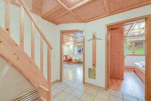 A spacious hallway with wooden flooring, a staircase, and a view into a room with a bed and a window. - Holiday Apartment "Sommerwind" with Mountain View, Garden & Balcony (Wackersberg)