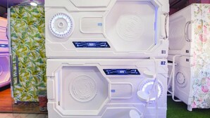 Una hilera de refrigeradores blancos de diseño moderno y futurista, con pantallas digitales, frente a un fondo de papel tapiz estampado y un suelo cubierto de alfombra verde.