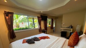 A hotel room with a large bed, a desk with a chair, a TV, and a window with curtains. - At Thara Aonang (Krabi)