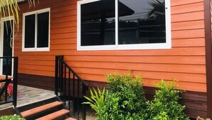 A two-story house with a wooden exterior, a front porch with steps, and two windows. - At Thara Aonang (Krabi)