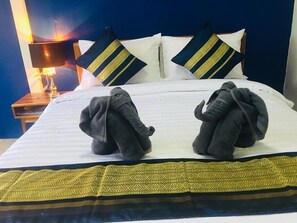 A neatly made bed with two towels shaped like elephants, a white pillow, and a blue headboard. - At Thara Aonang (Krabi)