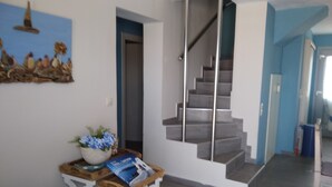 Un interior moderno con una escalera, una obra de arte en la pared y una mesita con un florero y una revista.