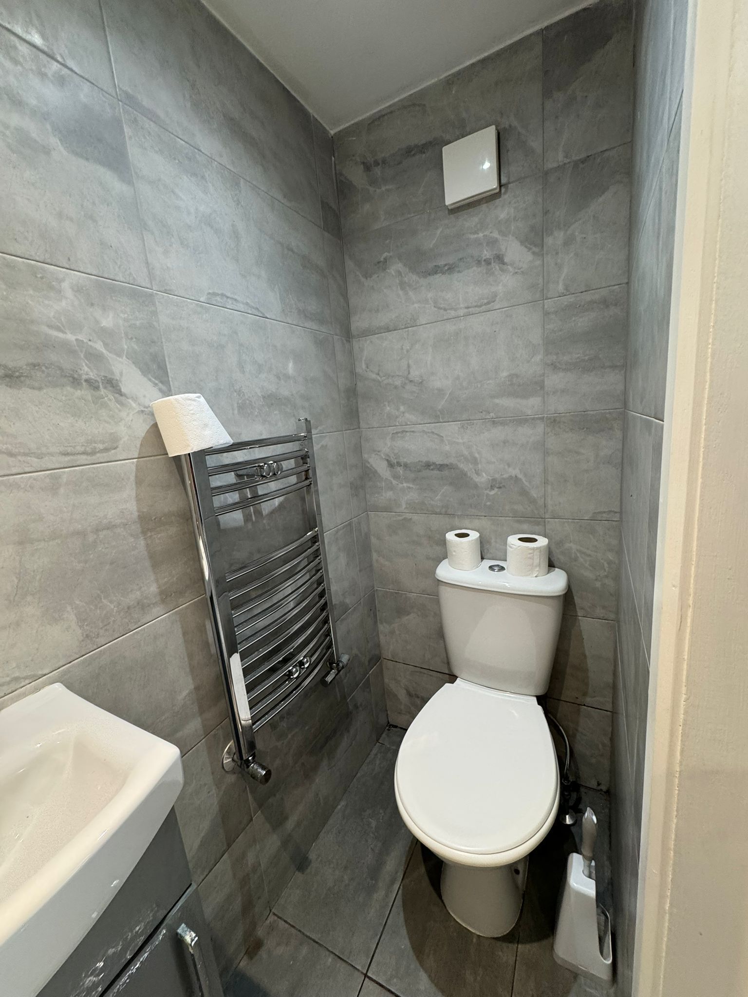 A small, modern bathroom with a toilet, a towel rack, and a sink.