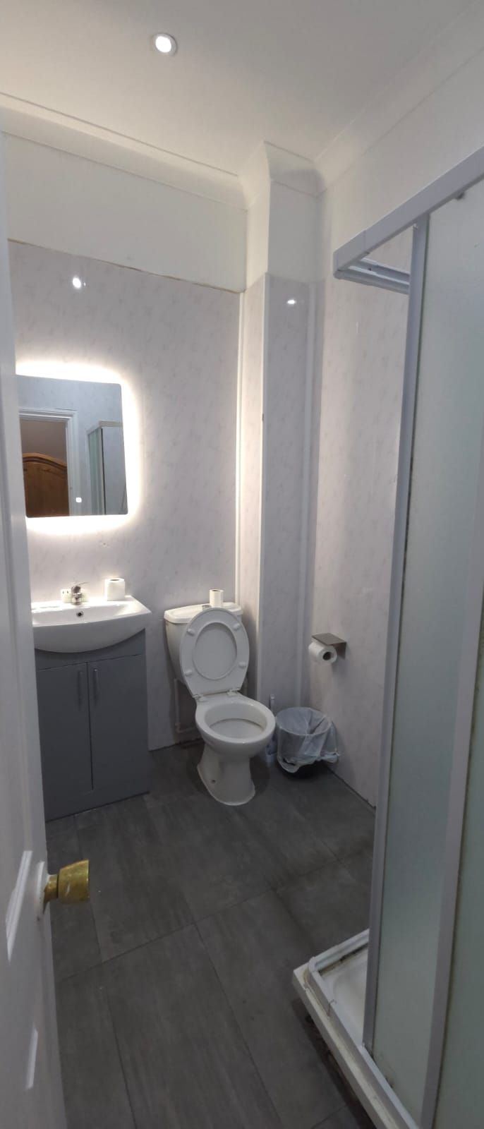 Une salle de bain comprenant des toilettes, un lavabo et un espace douche.