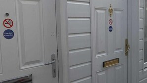 A white building with two doors, one marked with a 'B' and the other with an 'A'. Both doors have a fire door keep shut sign and a no smoking sign. - Golders Park Hotel (London)