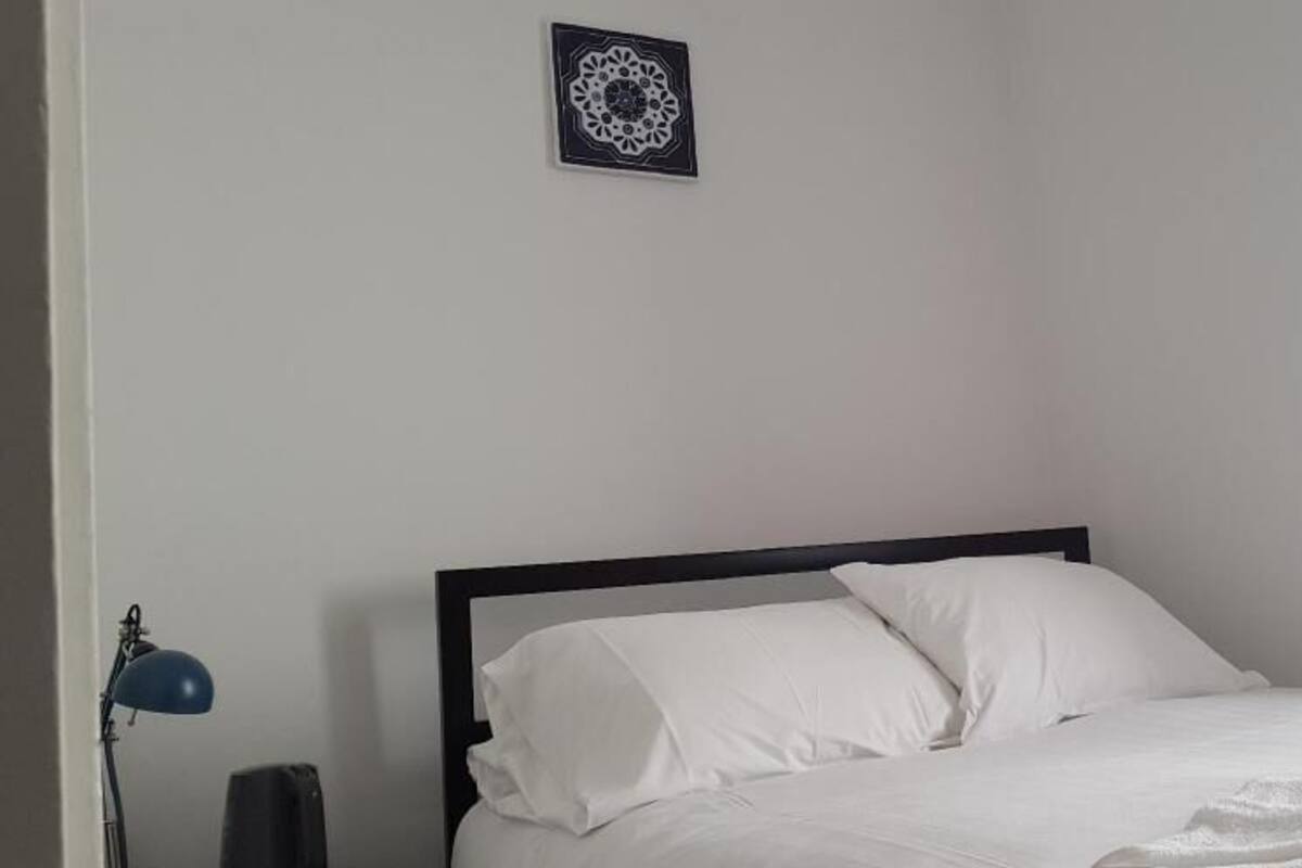 A bed with white bedding, a black headboard, and a single pillow.