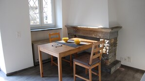 Un coin repas avec une table et des chaises en bois, une cheminée en pierre et une fenêtre donnant sur un beau paysage.