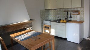Une cuisine de taille réduite, avec des meubles blancs, une petite cuisinière et un réfrigérateur.