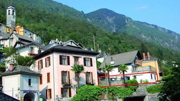 Une ville pittoresque située sur une colline, avec des bâtiments traditionnels, une église et une chaîne de montagnes en arrière-plan.