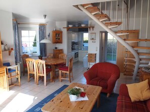 Un vaste espace de vie comprenant une table à manger en bois, un canapé rouge et un escalier menant à un niveau supérieur.