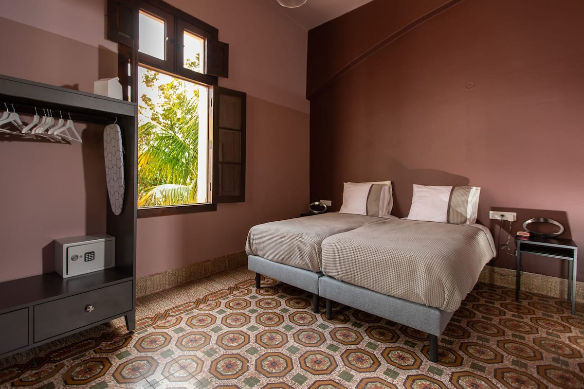 Un dormitorio con cama, armario, mesita de noche y ventana con vistas a zonas verdes.