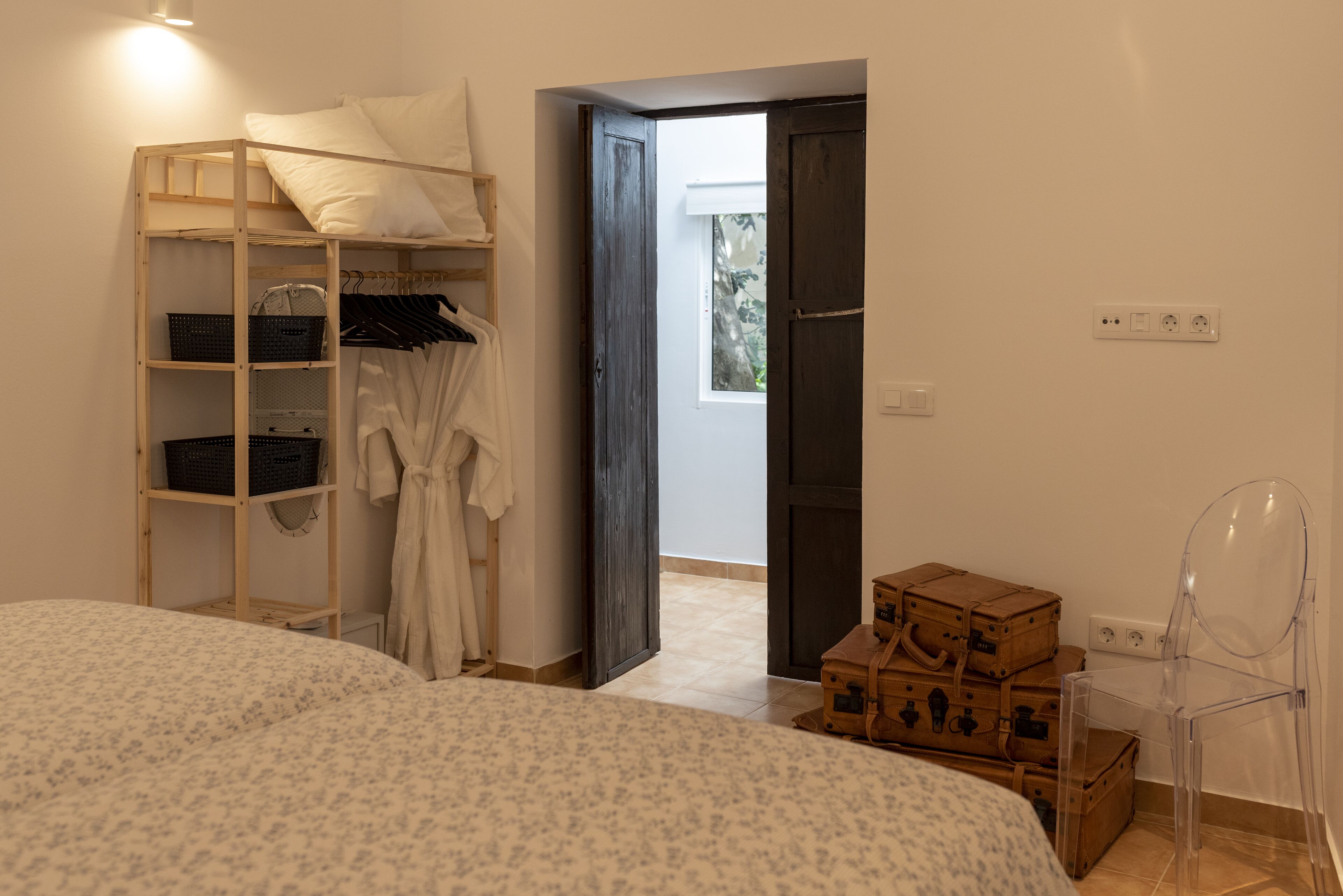 Een slaapkamer met een stapelbed, een houten garderobe, een tafeltje en een stoel.