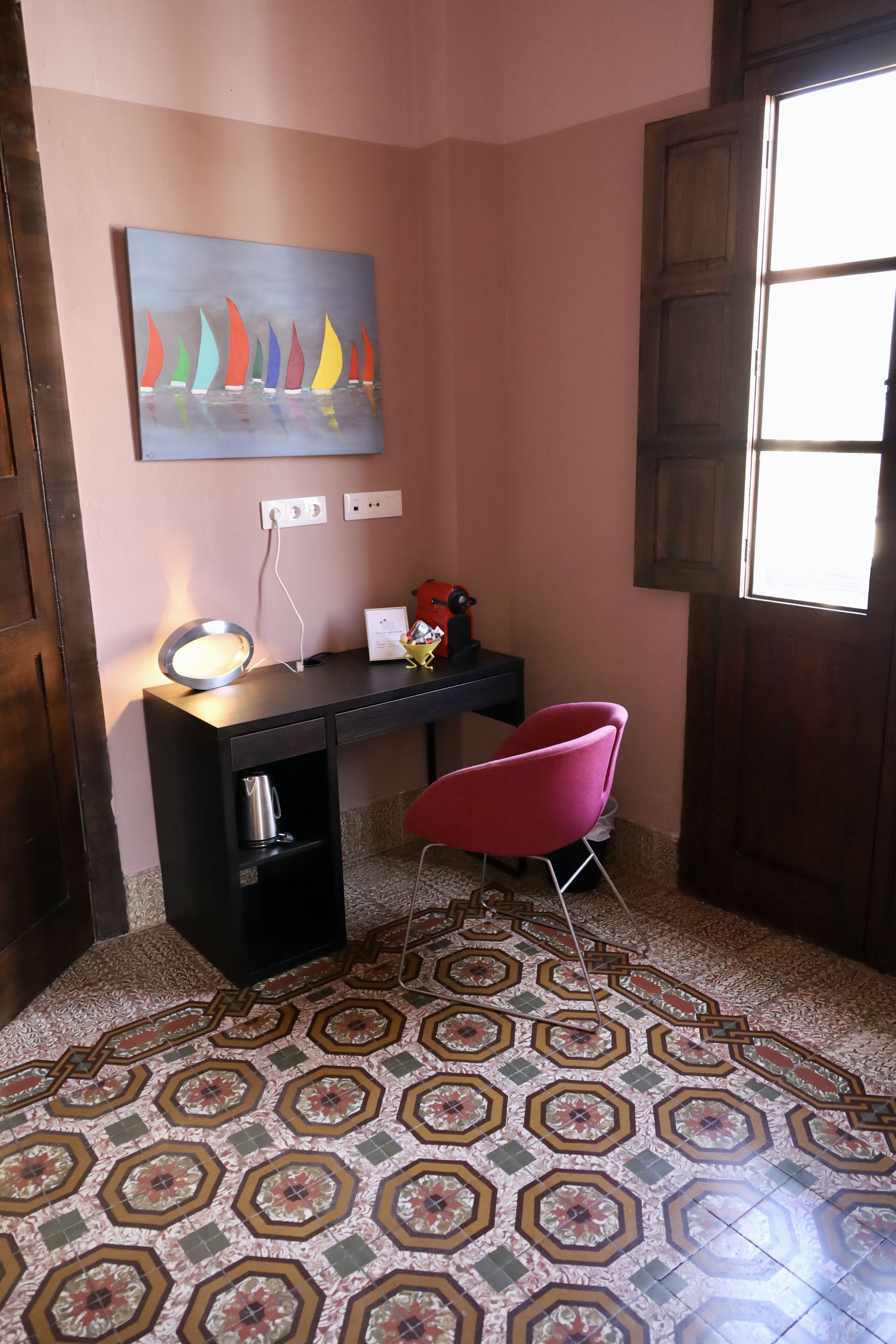 Una habitación con escritorio, silla, un cuadro y suelo estampado.