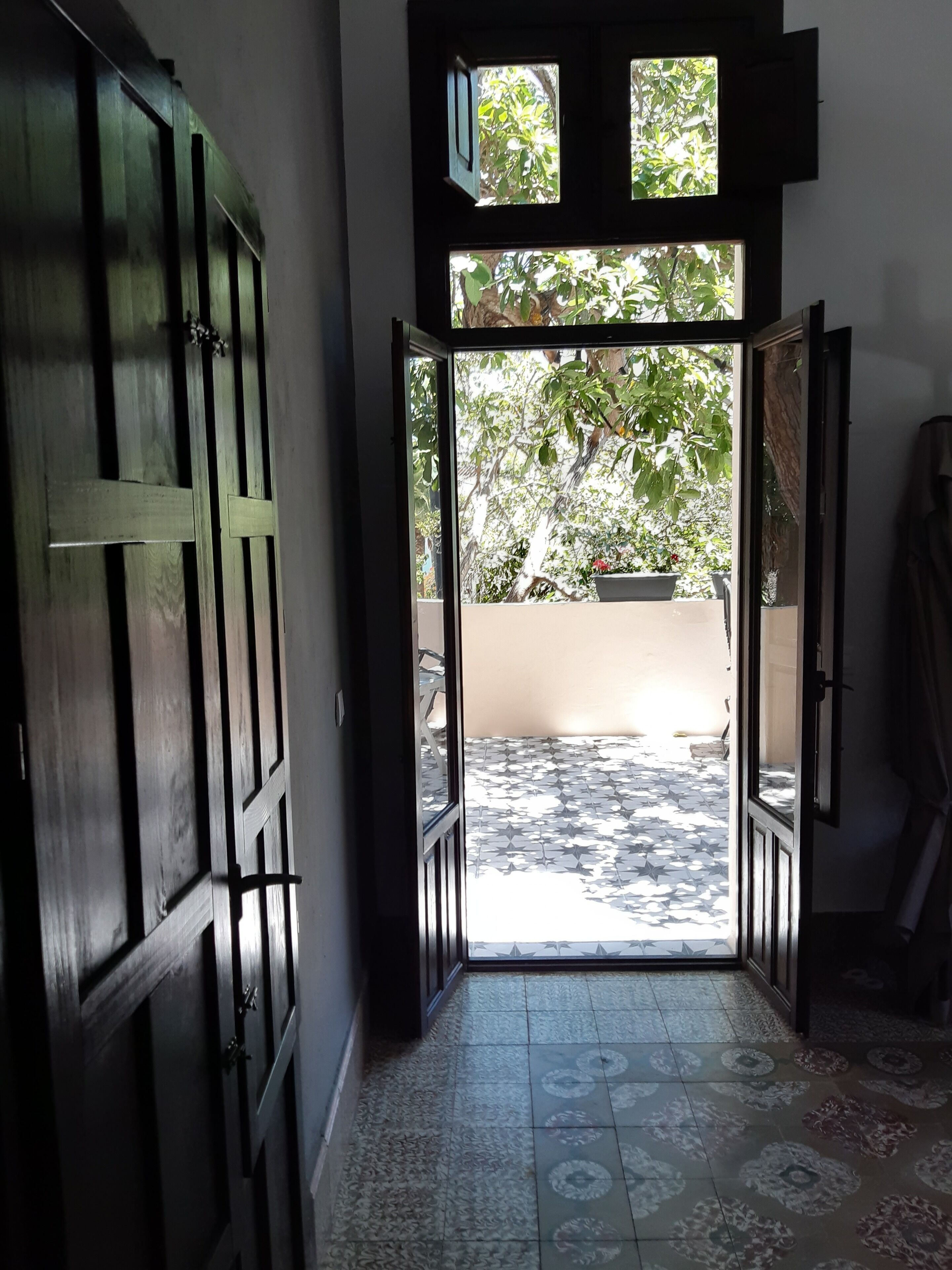An open doorway leading to a tiled patio with a view of greenery outside.