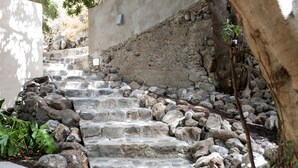A stone staircase with steps made of irregularly shaped stones, surrounded by a low stone wall and some greenery. - Villa Nestor (Ingenio)