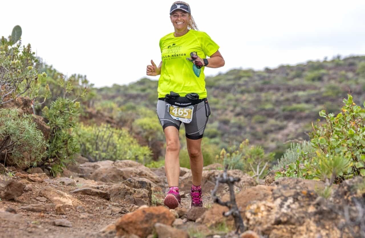 A person running on a rocky trail with sparse vegetation.