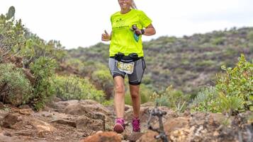 A person running on a rocky trail with sparse vegetation.