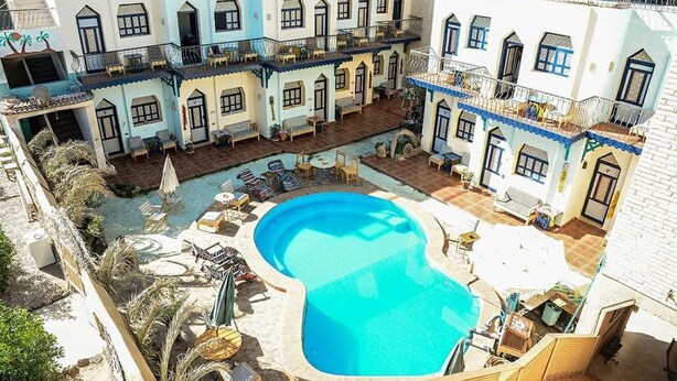 Un patio con piscina, sillas de descanso y un área de estar techada.
