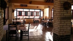 Un restaurante con paredes de ladrillo, ventanas amplias y mesas dispuestas para comer.