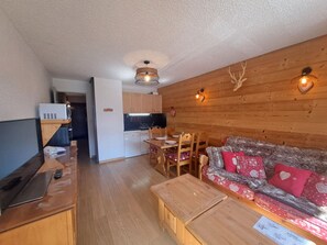 A cozy living room with a sofa, a wooden coffee table, and a television.