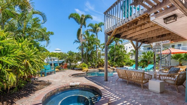 A pool area with a hot tub, lounge chairs, and a wooden deck.