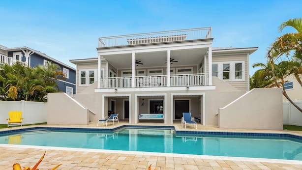 Une maison à deux étages avec une piscine, un balcon et un patio.