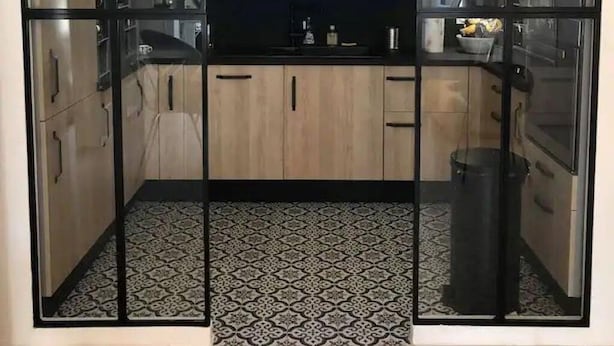 Eine moderne Küche mit einem schwarz-weißen Bodenmuster, einer zentralen Kochinsel und einem Fenster über der Spüle.