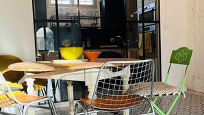 Ein Essbereich mit Tisch und Stühlen, einem großen Fenster und einer Küche im Hintergrund.