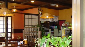 Interior de un restaurante japonés tradicional con muebles de madera, farolillos de papel colgantes y plantas en macetas.