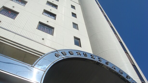 Un edificio moderno con una entrada curva y un cartel en un alfabeto extranjero.