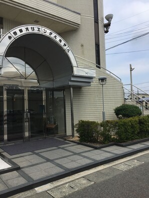 A building with a large arched entrance, a tiled facade, and a satellite dish on the roof. - Onoda Oriental Hotel (Sanyoonoda)
