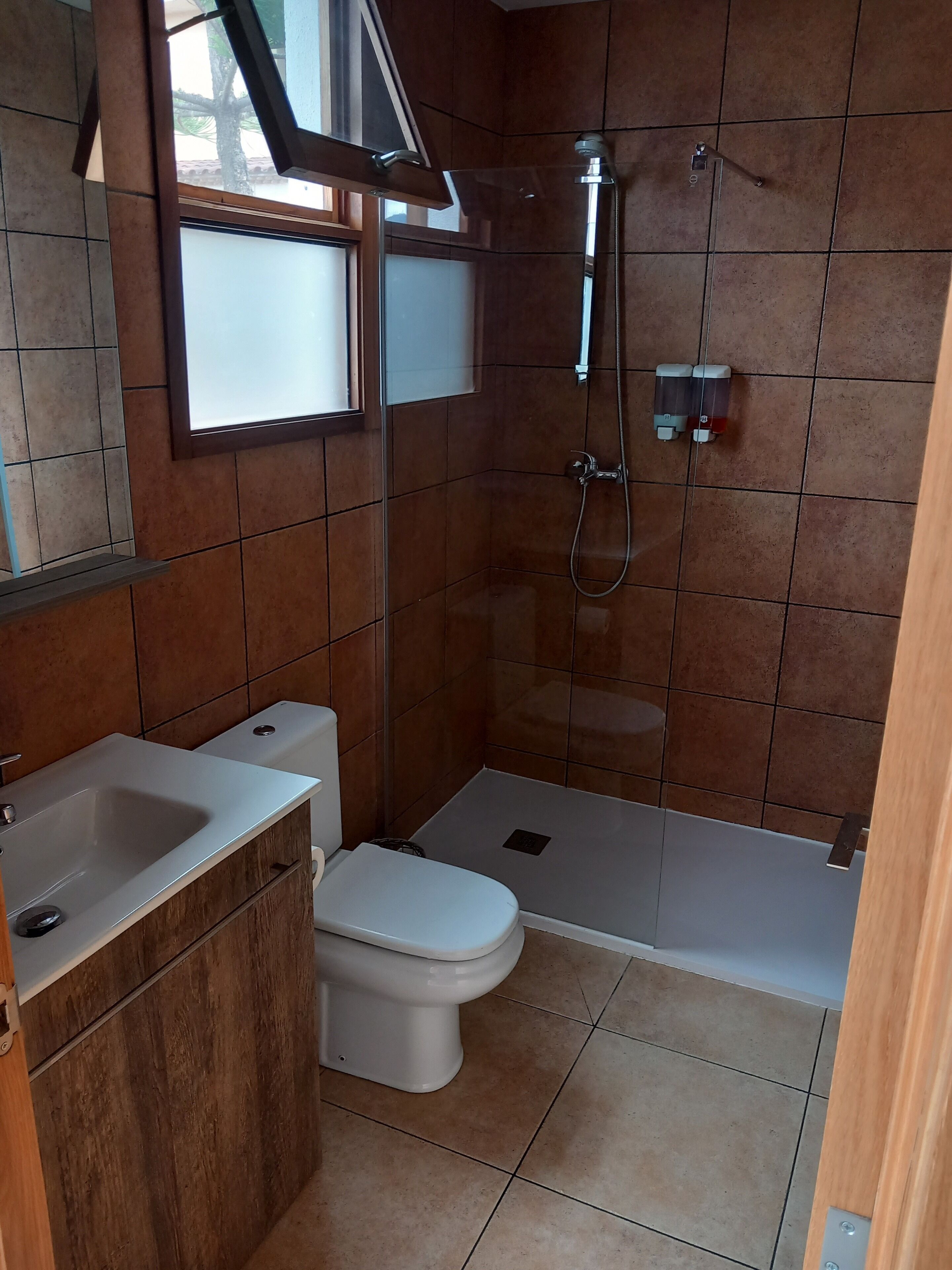 A small bathroom with a toilet, sink, and shower.